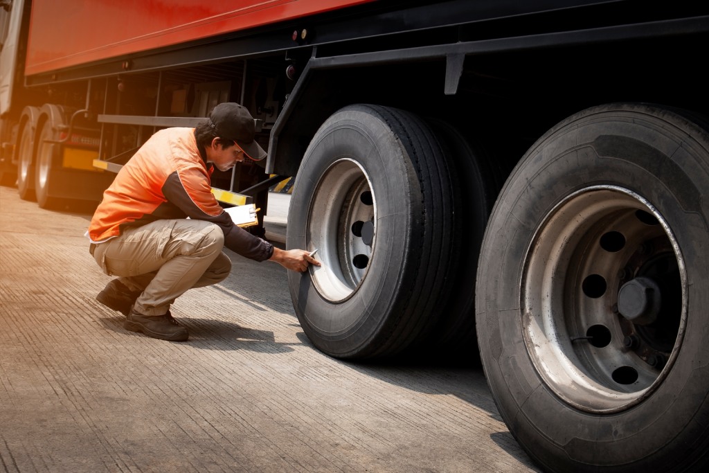 truck driver is inspecting safety daily check a truck wheels.
