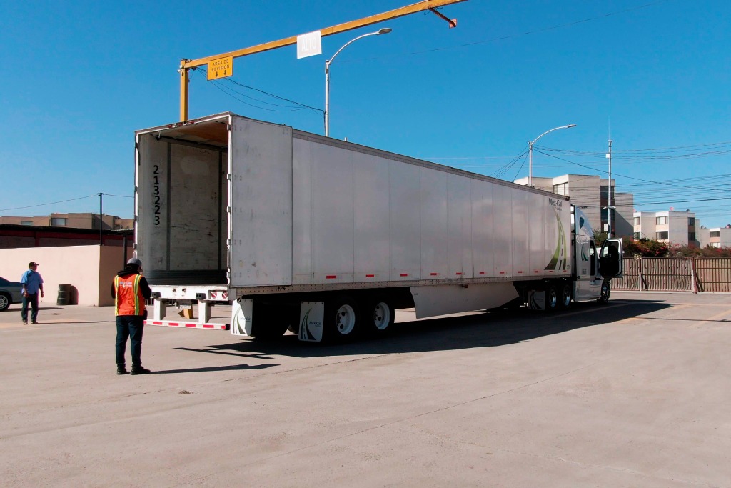 A man standing in front of a semi truck in a truck yard