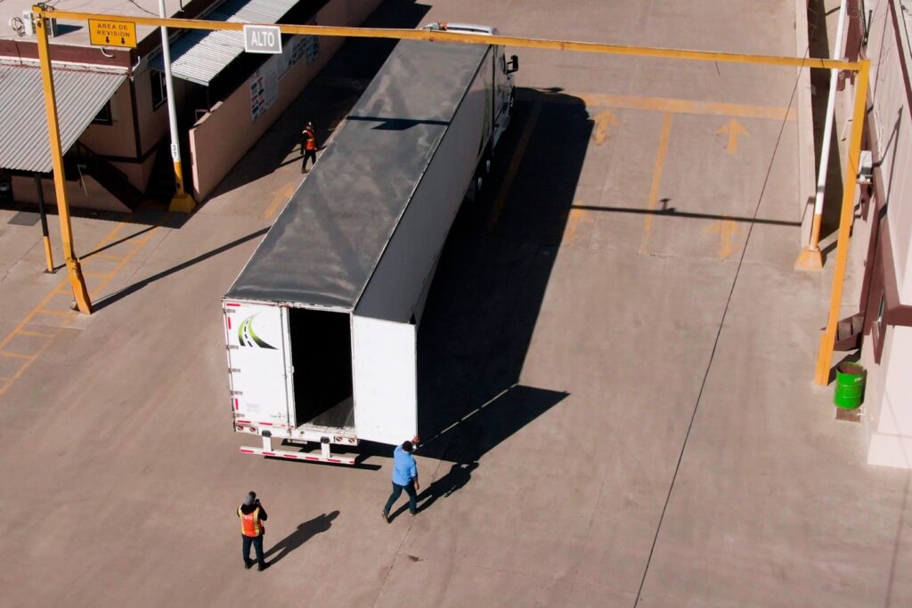 Truck with open rear door and two people.