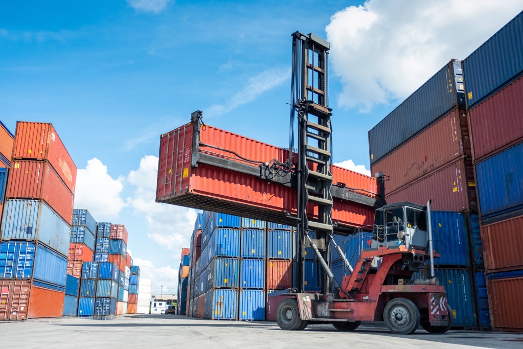 Forklift truck in shipyard with containers box and sky on background.